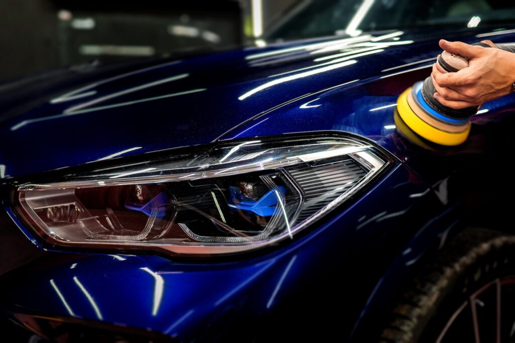 Car detailing shop hands with orbital polisher in auto repair shop, exterior specialty clean