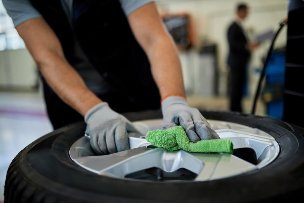 Close-up of a mechanic cleaning repaired car tire with a cloth. Partnerships available!